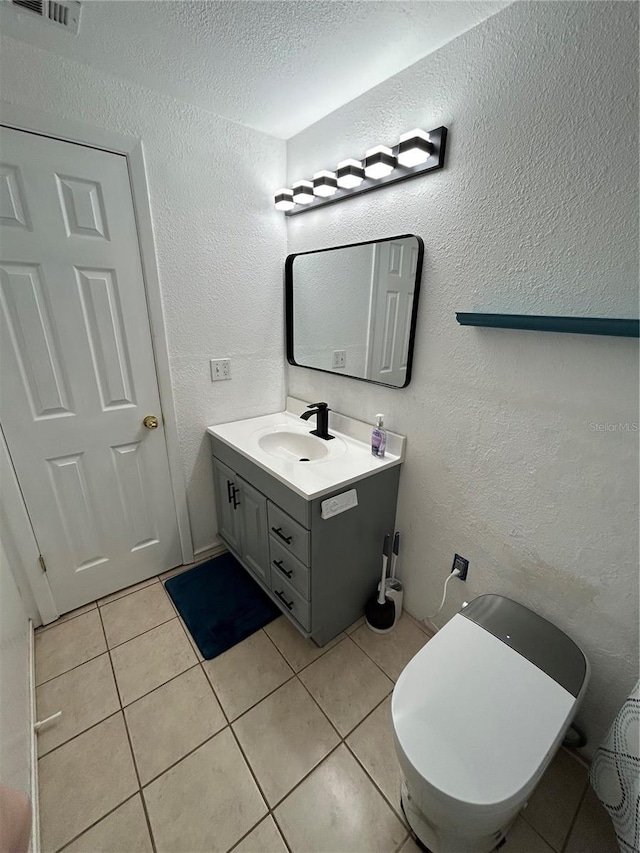 bathroom featuring tile patterned floors, vanity, a textured ceiling, and toilet