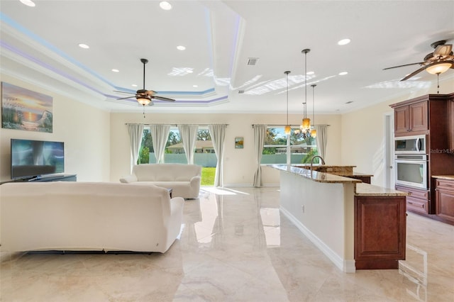 living room with a raised ceiling, ceiling fan, ornamental molding, and sink