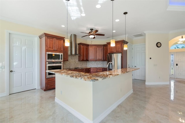 kitchen featuring a large island with sink, wall chimney exhaust hood, hanging light fixtures, and appliances with stainless steel finishes