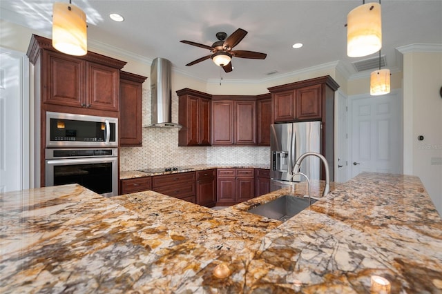 kitchen with wall chimney range hood, hanging light fixtures, crown molding, sink, and appliances with stainless steel finishes