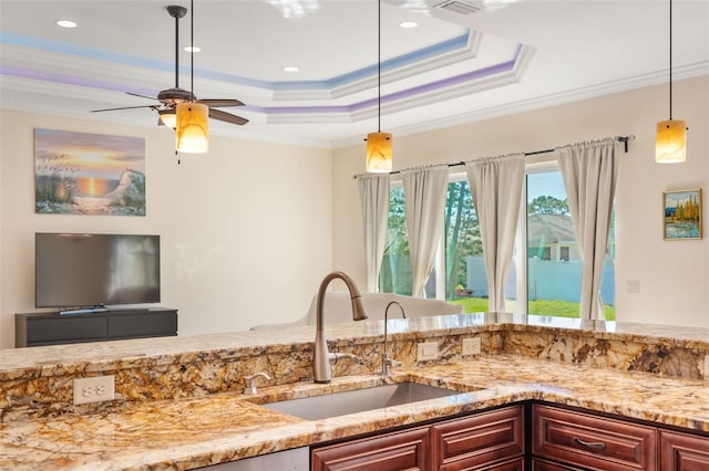 kitchen featuring ornamental molding, a raised ceiling, ceiling fan, sink, and pendant lighting