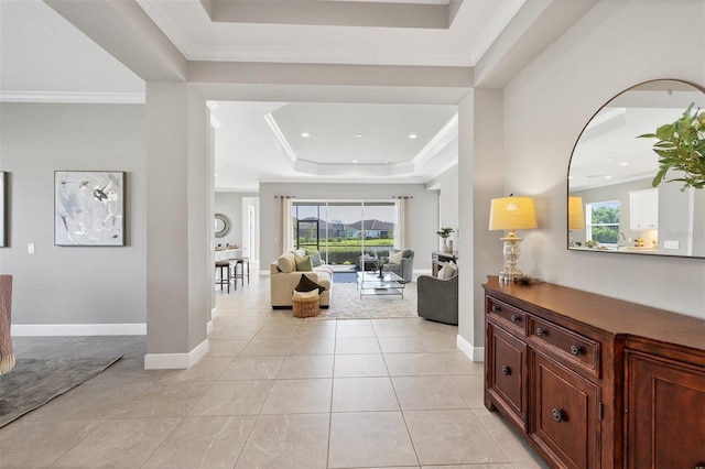 entrance foyer featuring light tile patterned flooring, a healthy amount of sunlight, a raised ceiling, and ornamental molding