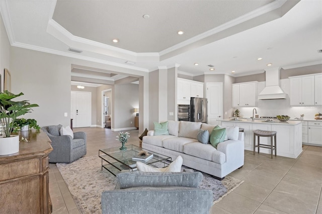 tiled living room with ornamental molding and a tray ceiling