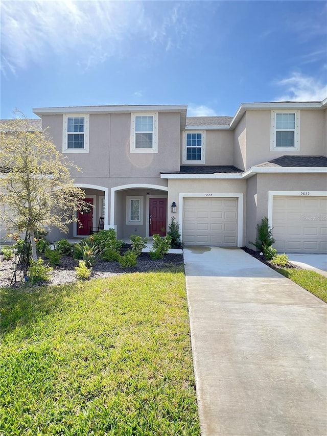 view of front of property featuring driveway, a front lawn, an attached garage, and stucco siding