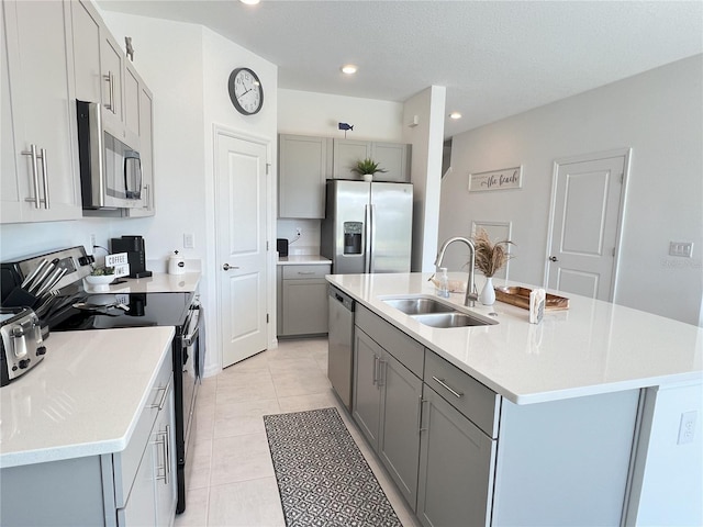 kitchen featuring appliances with stainless steel finishes, gray cabinets, light countertops, a sink, and light tile patterned flooring