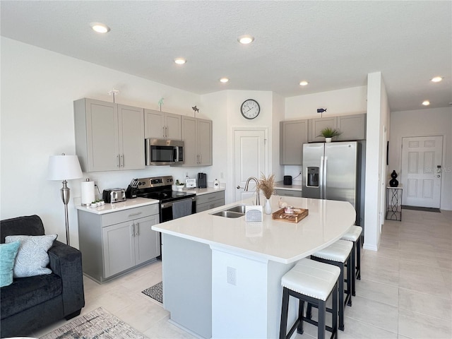 kitchen with stainless steel appliances, gray cabinets, and a breakfast bar area