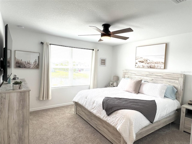 carpeted bedroom featuring a textured ceiling, ceiling fan, and baseboards