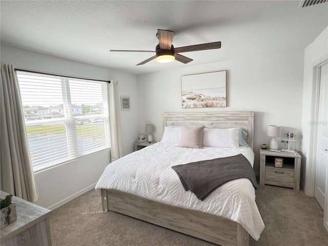 carpeted bedroom with visible vents, ceiling fan, and a textured ceiling