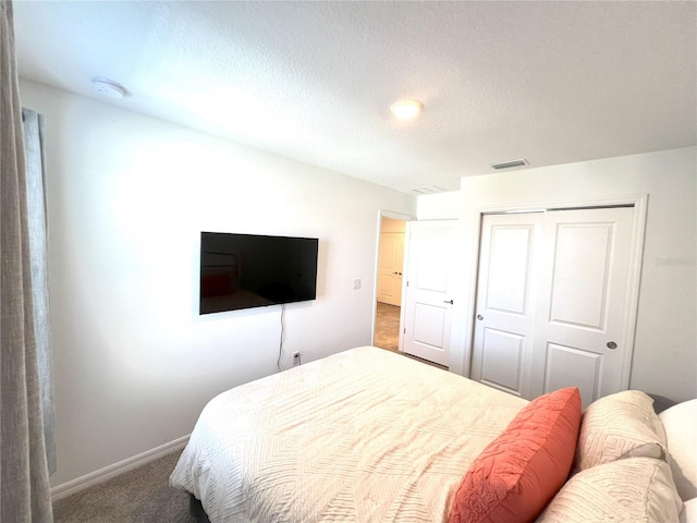 carpeted bedroom with a textured ceiling and a closet