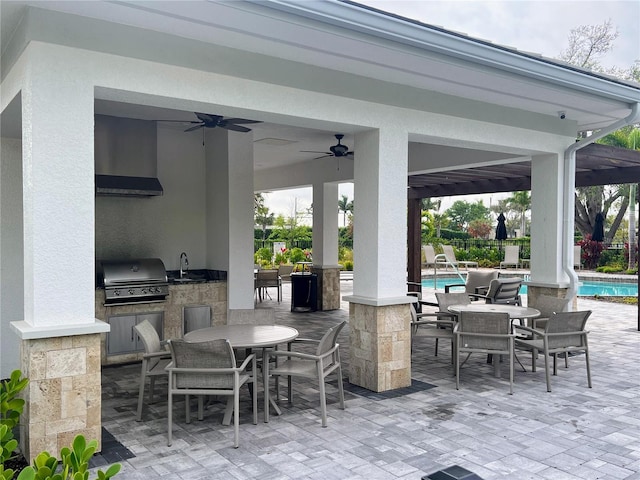 view of patio with area for grilling, sink, grilling area, ceiling fan, and a fenced in pool