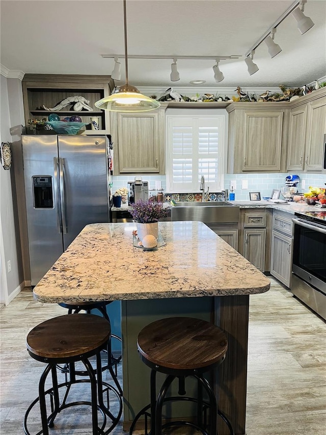 kitchen with light hardwood / wood-style floors, stainless steel appliances, sink, a kitchen island, and pendant lighting