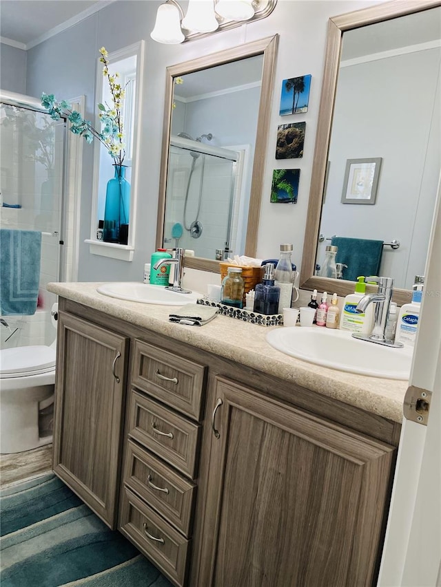 bathroom with crown molding, vanity, toilet, and a shower with shower door