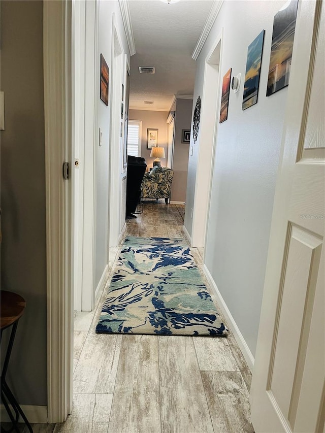 hall with light wood-type flooring and crown molding