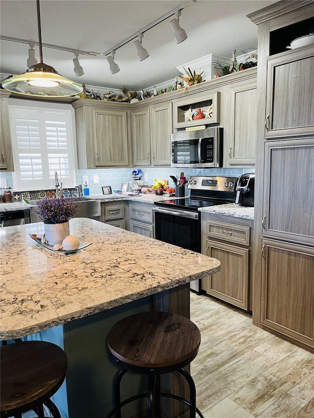 kitchen featuring stainless steel appliances, pendant lighting, light stone countertops, a kitchen breakfast bar, and light hardwood / wood-style flooring