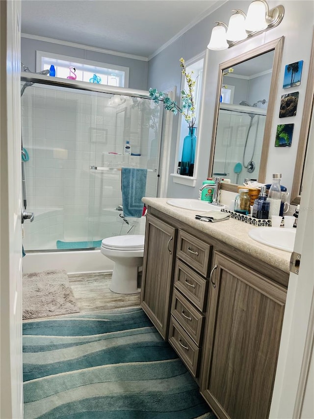 bathroom featuring toilet, vanity, crown molding, and a shower with shower door