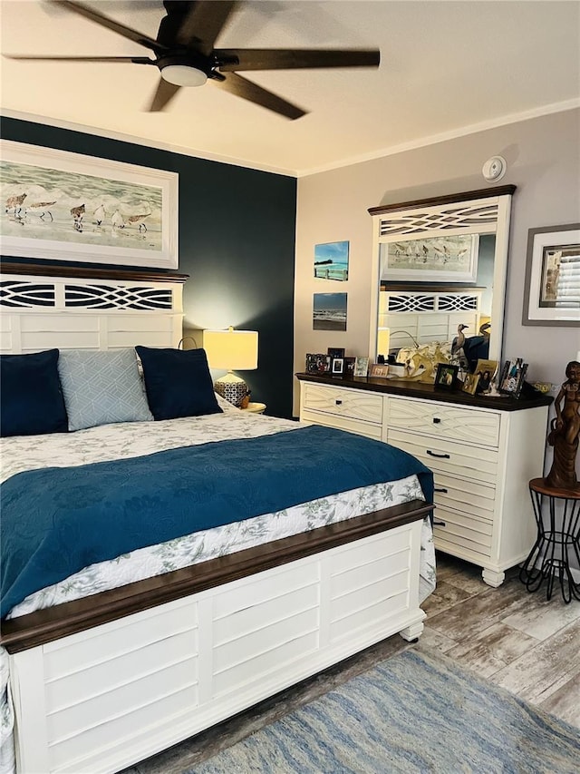 bedroom with wood-type flooring, ceiling fan, and crown molding