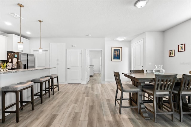 dining room featuring light wood-type flooring and a textured ceiling