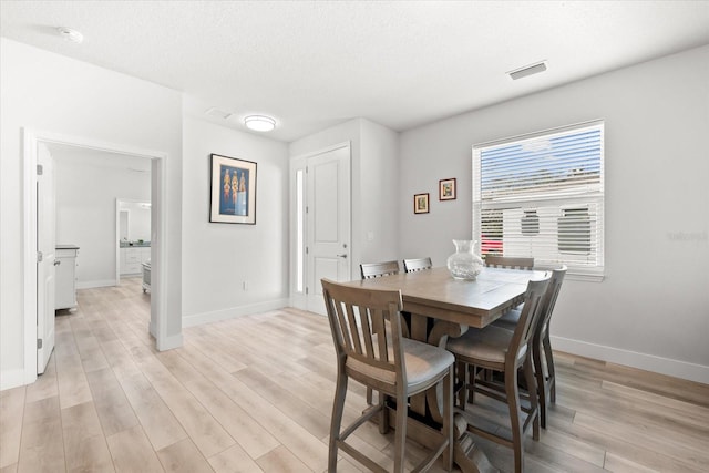 dining area with light hardwood / wood-style floors and a textured ceiling