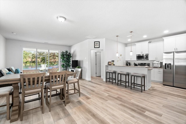 dining room featuring light wood-type flooring and a textured ceiling