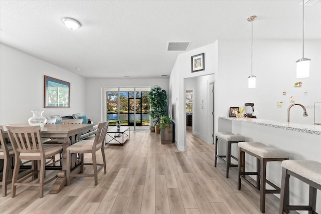 dining room with light wood-type flooring and a textured ceiling