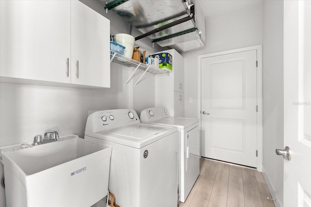 laundry area with cabinets, light hardwood / wood-style flooring, sink, and washer and clothes dryer