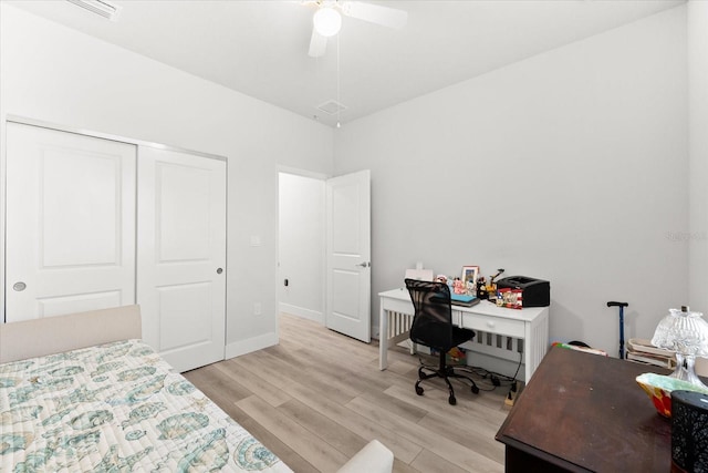 bedroom with light wood-type flooring, ceiling fan, and a closet