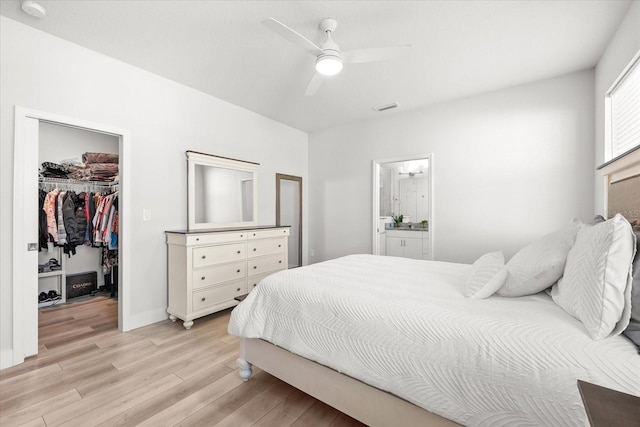 bedroom with ensuite bathroom, ceiling fan, light hardwood / wood-style flooring, a walk in closet, and a closet