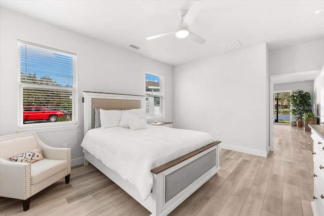 bedroom featuring ceiling fan, multiple windows, and light hardwood / wood-style floors