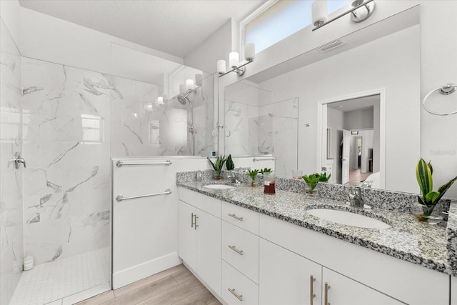 bathroom featuring vanity, hardwood / wood-style floors, a tile shower, and a textured ceiling