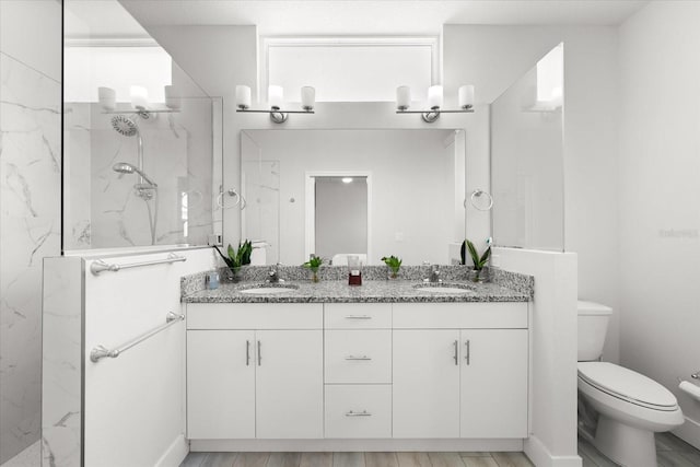 bathroom featuring toilet, vanity, wood-type flooring, and a tile shower