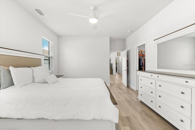 bedroom featuring light hardwood / wood-style flooring, ceiling fan, a spacious closet, and a closet