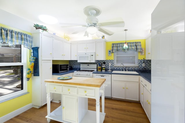 kitchen with white appliances, decorative backsplash, sink, and white cabinets