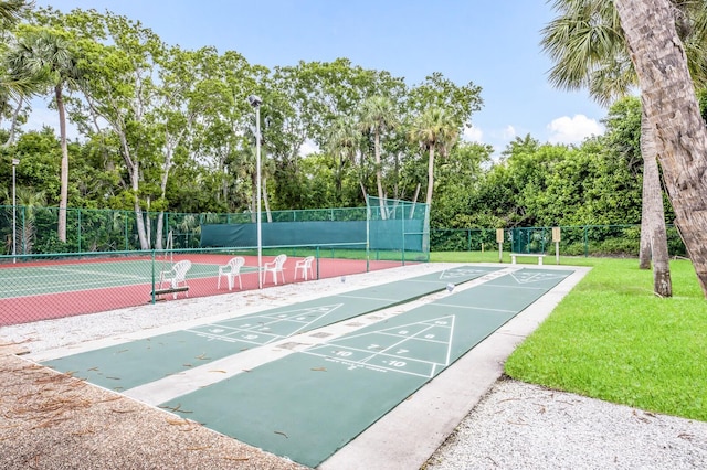 view of home's community featuring a lawn and tennis court