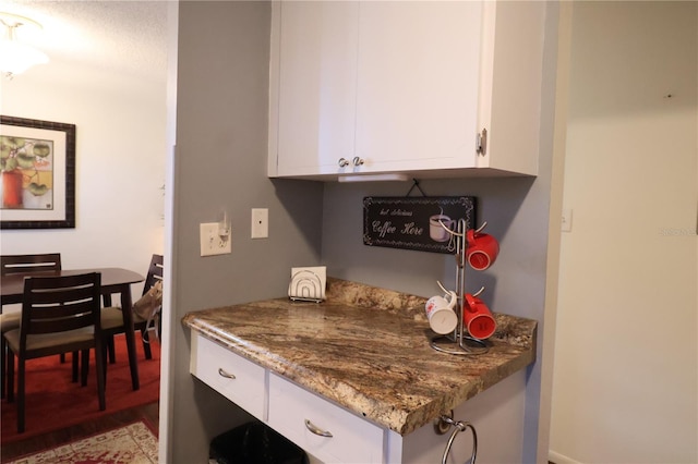 kitchen with white cabinets, stone countertops, and light wood-type flooring