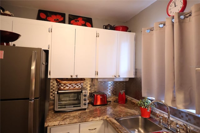 kitchen featuring tasteful backsplash, stainless steel refrigerator, sink, and white cabinets