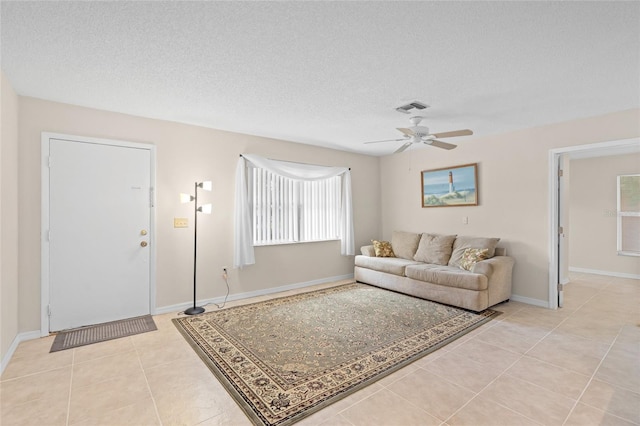 living room featuring ceiling fan, a textured ceiling, a wealth of natural light, and light tile patterned floors