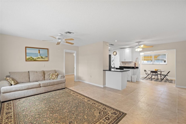 tiled living room with a textured ceiling and ceiling fan