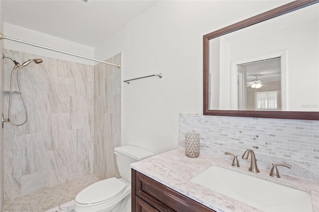 bathroom with tiled shower, toilet, tasteful backsplash, vanity, and ceiling fan