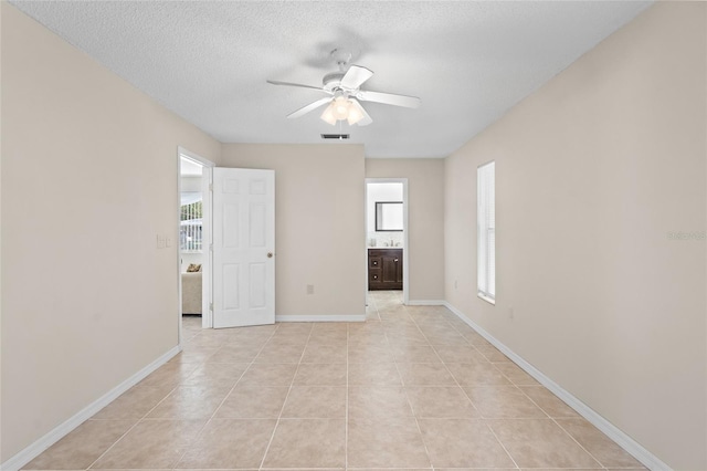 unfurnished room featuring ceiling fan, a healthy amount of sunlight, a textured ceiling, and light tile patterned floors