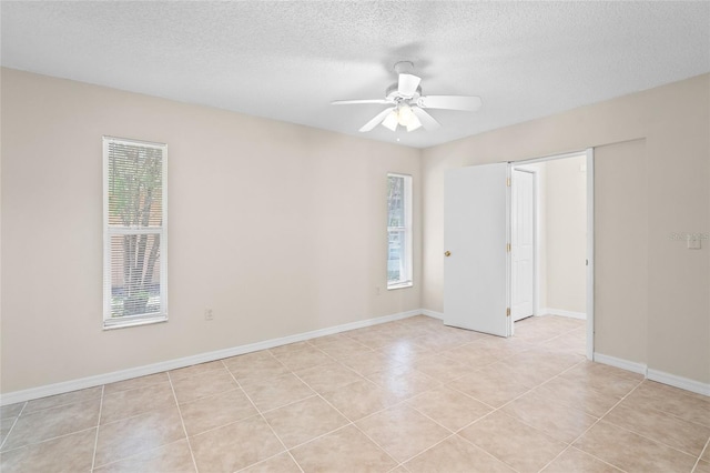 tiled spare room with a textured ceiling, a healthy amount of sunlight, and ceiling fan