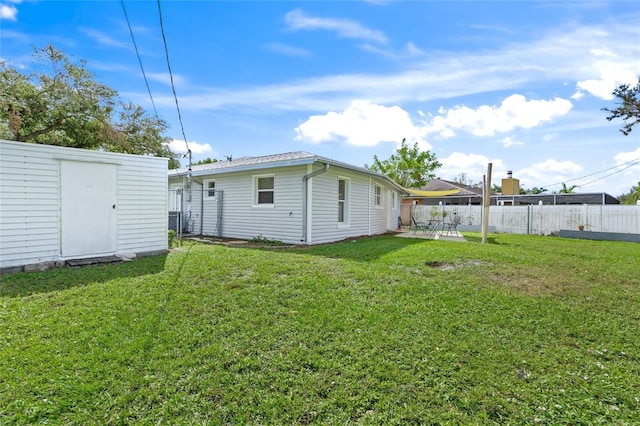 rear view of property featuring a patio area, a storage shed, and a lawn