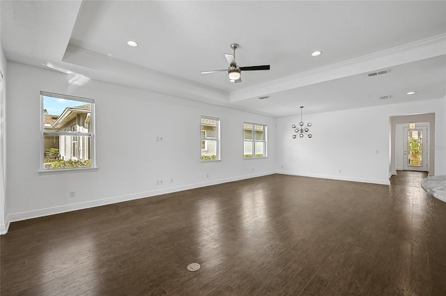 spare room with dark wood-type flooring, ceiling fan with notable chandelier, and a healthy amount of sunlight