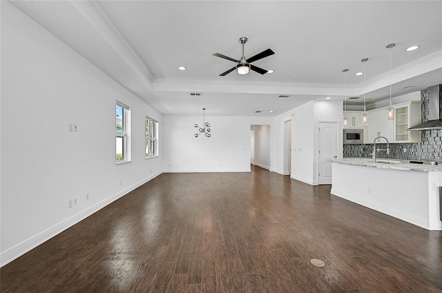 unfurnished living room featuring crown molding, a raised ceiling, and dark hardwood / wood-style flooring