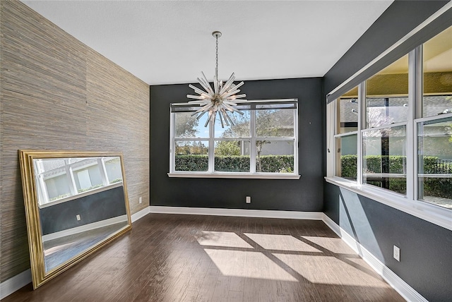 unfurnished dining area featuring a chandelier and dark hardwood / wood-style floors