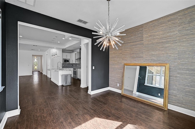 unfurnished living room featuring tile walls, dark wood-type flooring, sink, and a notable chandelier