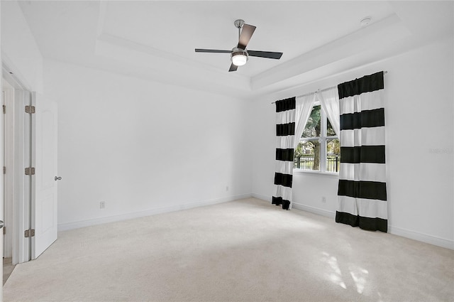 carpeted spare room with ceiling fan and a tray ceiling