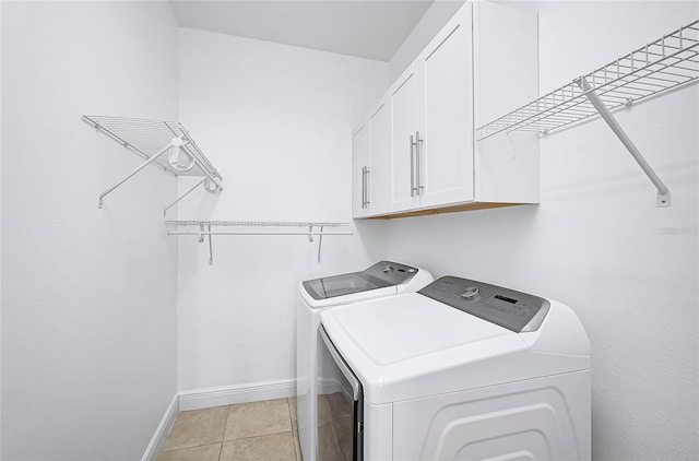 laundry area with cabinets, separate washer and dryer, and light tile patterned floors