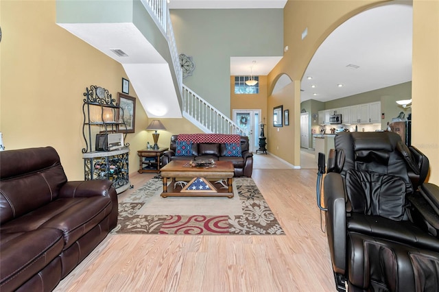 living room with a towering ceiling and light wood-type flooring