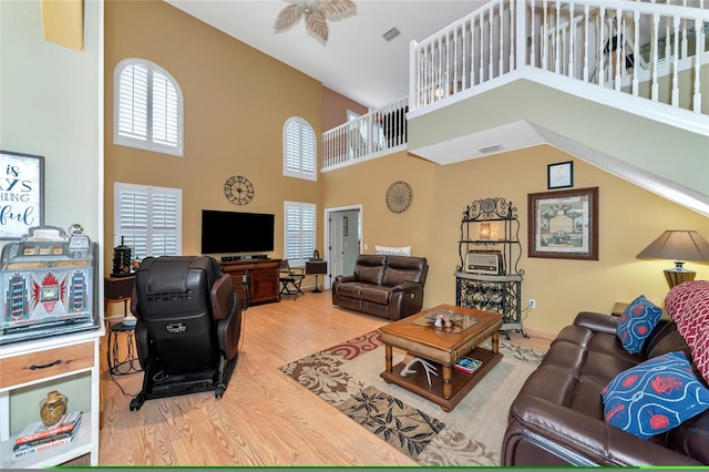 living room featuring hardwood / wood-style floors, ceiling fan, and a high ceiling