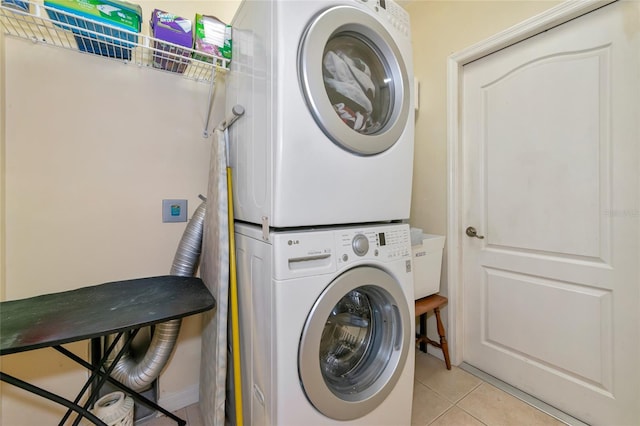 laundry room with stacked washer and clothes dryer and light tile patterned floors